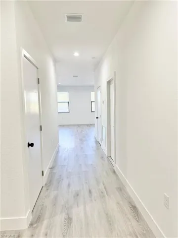 Hallway with light wood-style flooring and recessed lighting