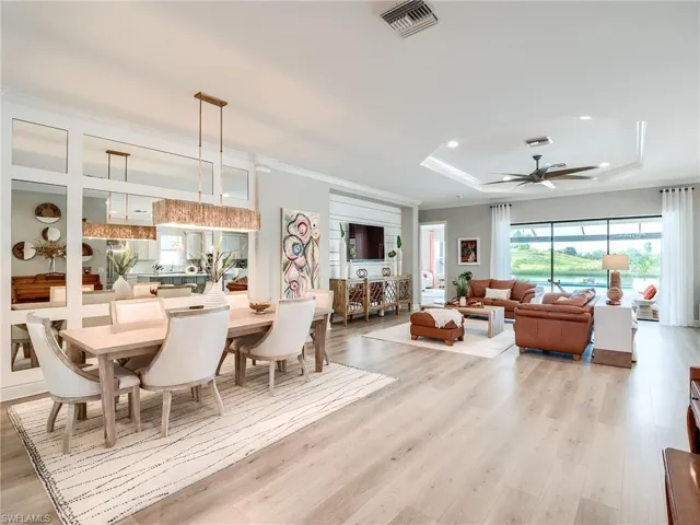 Dining area with light hardwood / wood-style flooring, a tray ceiling, crown molding, and ceiling fan