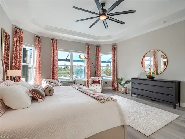 Bedroom featuring crown molding, a raised ceiling, light hardwood / wood-style floors, and ceiling fan