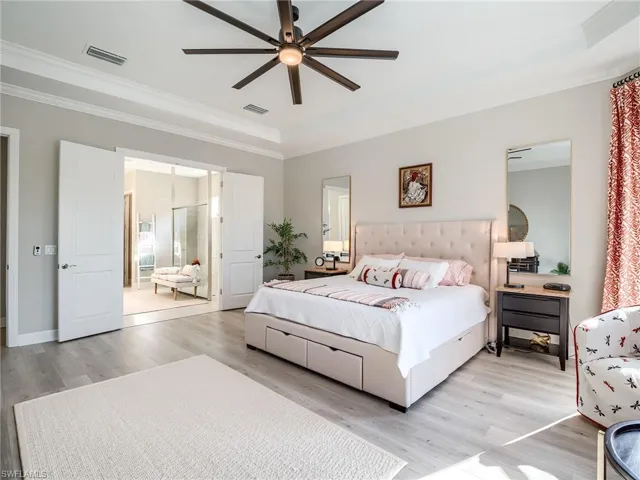Bedroom featuring ceiling fan, a raised ceiling, ornamental molding, and light hardwood / wood-style floors
