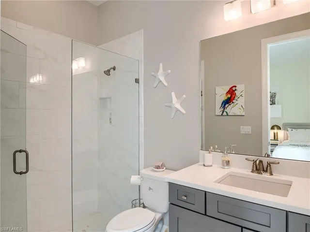 Bathroom featuring toilet, vanity, and a shower with door