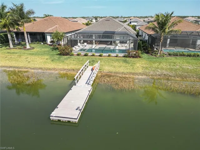 View of dock featuring a fenced in pool, a lawn, a water view, and glass enclosure