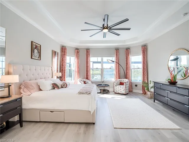 Bedroom with ceiling fan, a tray ceiling, light hardwood / wood-style flooring, and crown molding