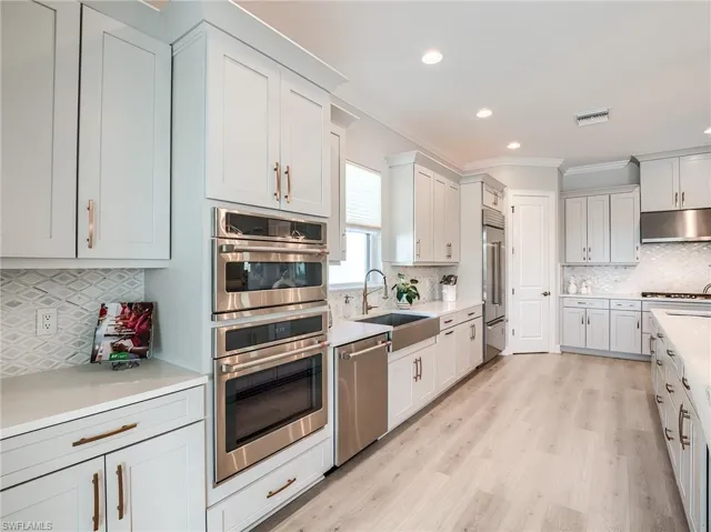 Kitchen with white cabinets, tasteful backsplash, stainless steel appliances, and sink