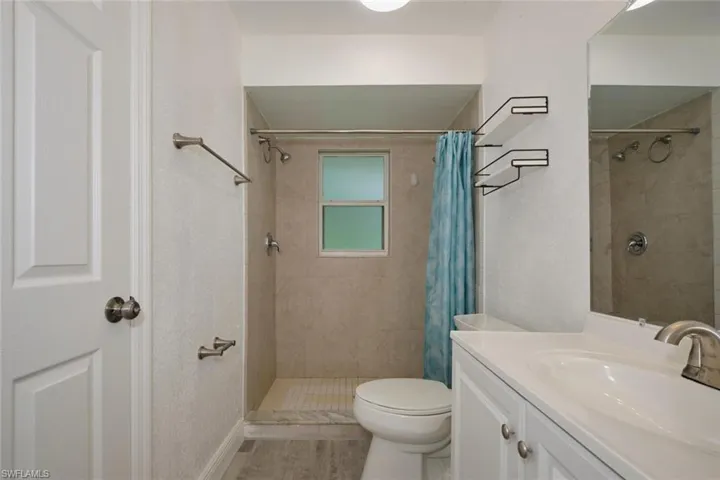 Bathroom with walk in shower, vanity, toilet, and hardwood / wood-style flooring