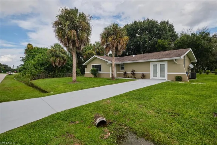Ranch-style house with central air condition unit, french doors, and a front yard
