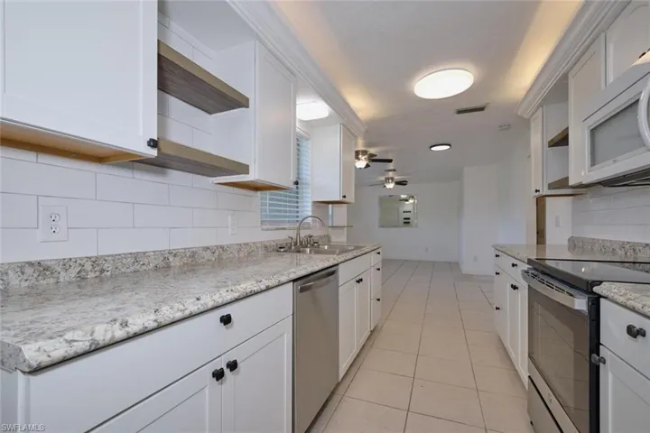 Kitchen with ceiling fan, white cabinets, sink, tasteful backsplash, and appliances with stainless steel finishes