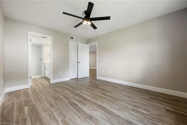 Unfurnished bedroom featuring light wood finished floors, ensuite bathroom, and ceiling fan