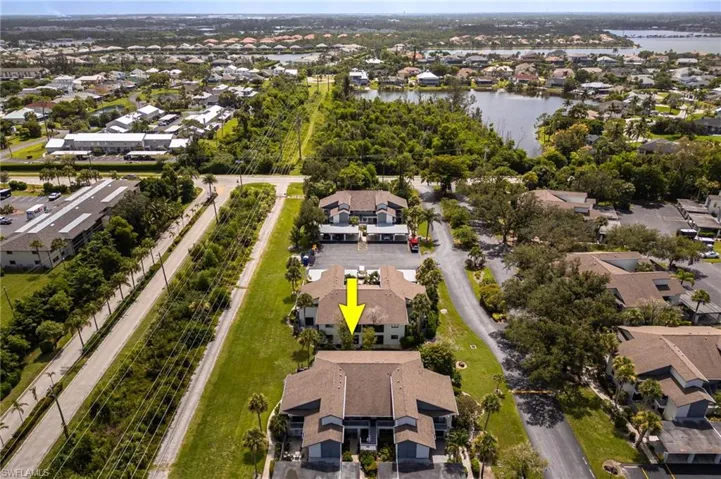 Aerial view of property and surrounding area featuring nearby suburban area and a large body of water