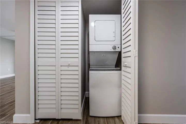 Laundry area featuring estacked washer and dryer and wood finished floors
