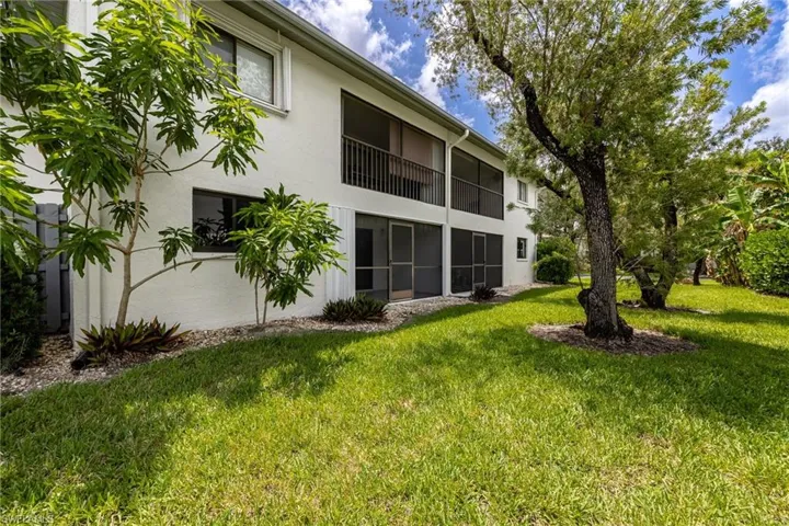 Back of house with stucco siding and a lawn