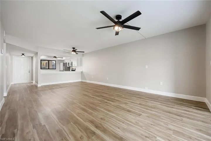 Unfurnished living room featuring light wood-style floors and a ceiling fan