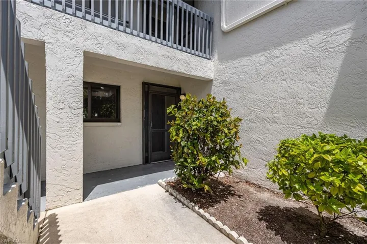 View of exterior entry featuring stucco siding and a balcony