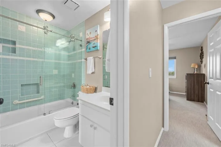 Full bathroom with bath / shower combo with glass door, toilet, and vanity