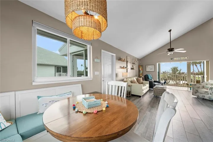Dining space with ceiling fan with notable chandelier, wood-type flooring, and vaulted ceiling