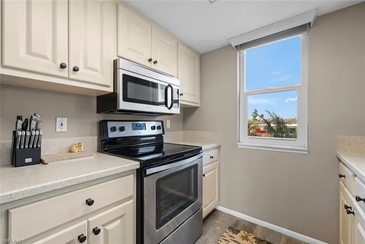 Kitchen with dark hardwood / wood-style flooring, white cabinetry, and appliances with stainless steel finishes
