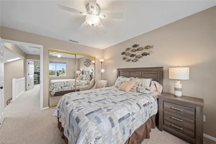 Bedroom with a closet, ceiling fan, and light colored carpet