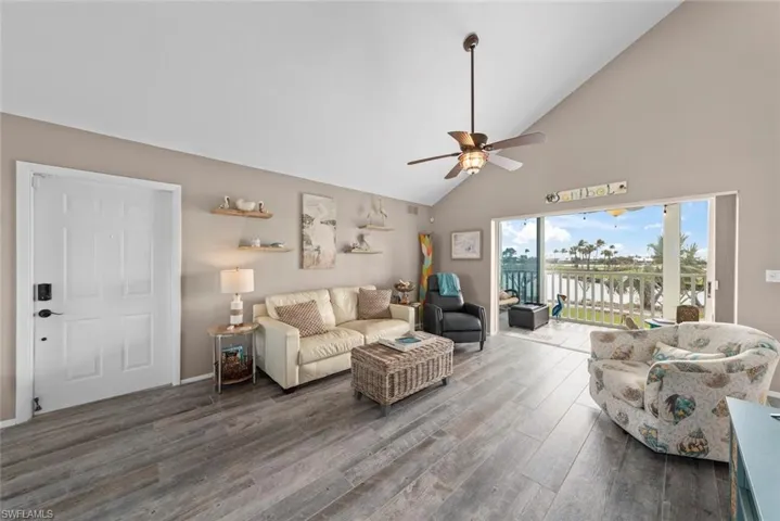 Living room with high vaulted ceiling, ceiling fan, and dark hardwood / wood-style flooring