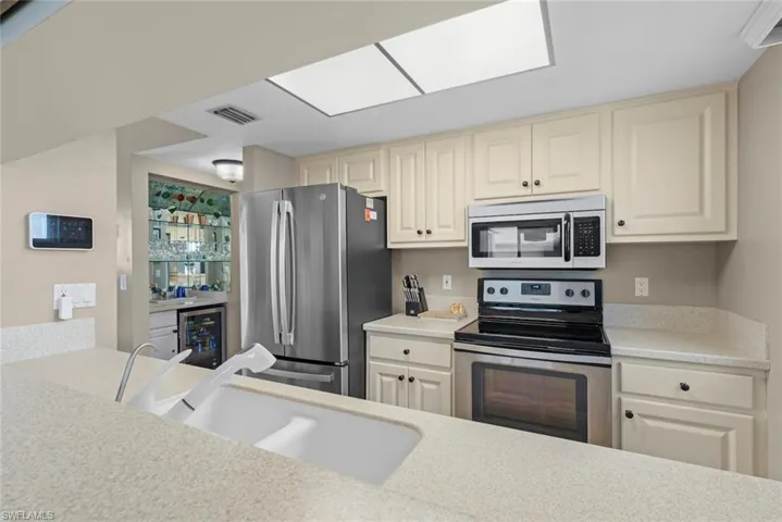 Kitchen with sink, stainless steel appliances, cream cabinets, and wine cooler