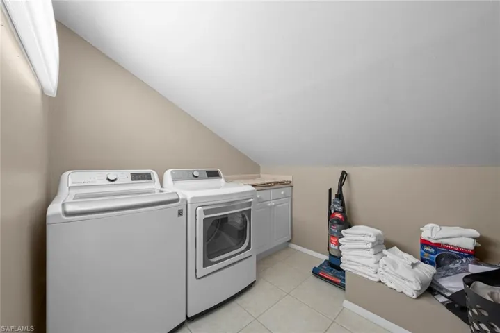 Laundry room featuring cabinets, light tile patterned floors, and washing machine and dryer