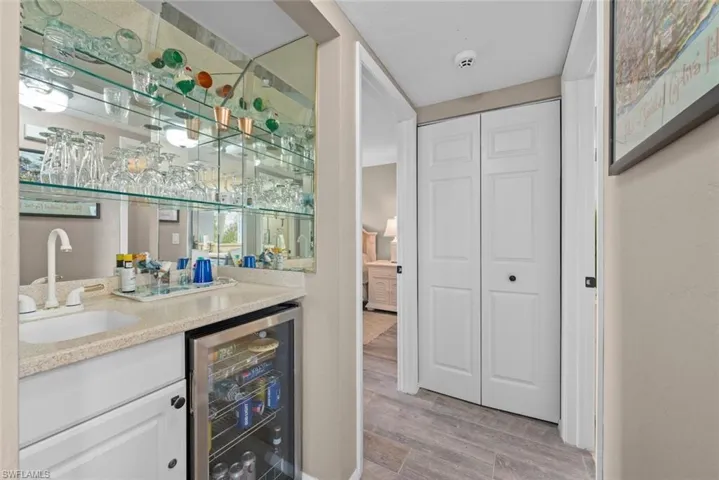 Bar featuring light hardwood / wood-style floors, sink, white cabinetry, and beverage cooler