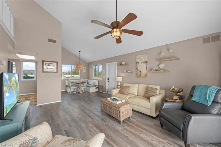 Living room with high vaulted ceiling, hardwood / wood-style floors, and ceiling fan
