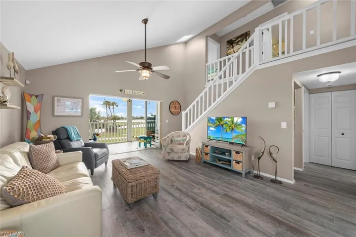 Living room featuring high vaulted ceiling, ceiling fan, and dark hardwood / wood-style flooring
