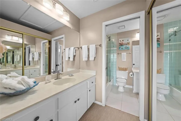 Bathroom featuring a shower with door, toilet, tile patterned floors, and vanity