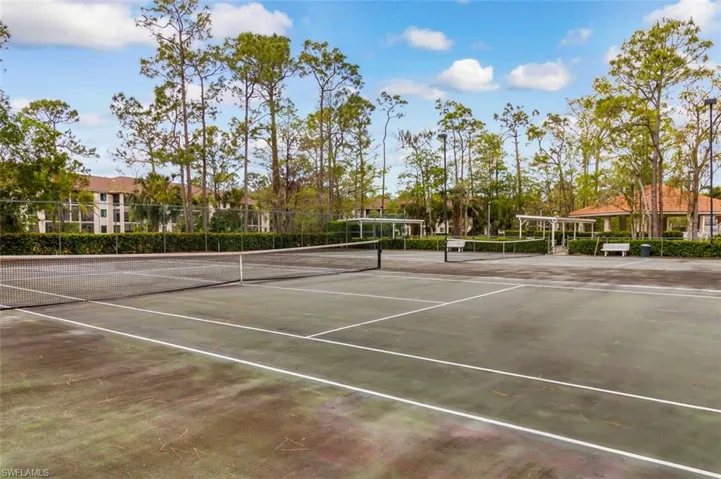 View of tennis court featuring fence and community basketball court