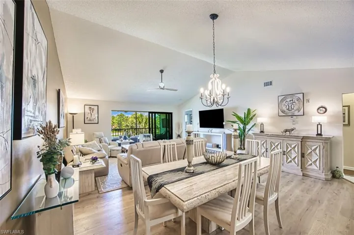 Dining space featuring lofted ceiling, a ceiling fan, light wood-style flooring, a chandelier, and baseboards