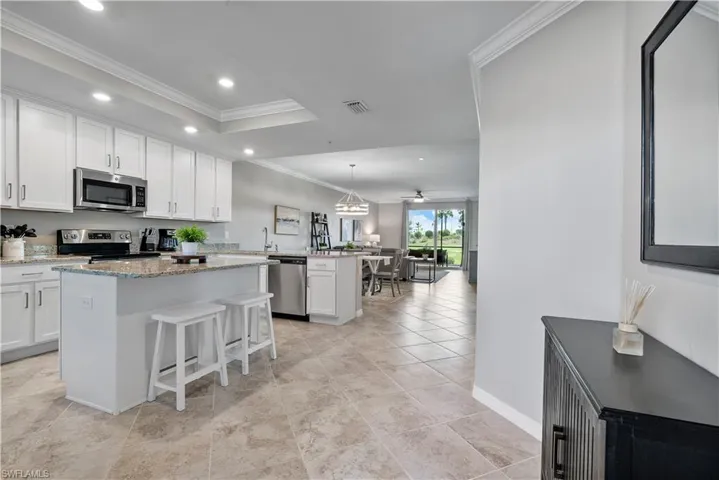 Kitchen featuring decorative light fixtures, a kitchen island, ornamental molding, a breakfast bar, and white cabinets