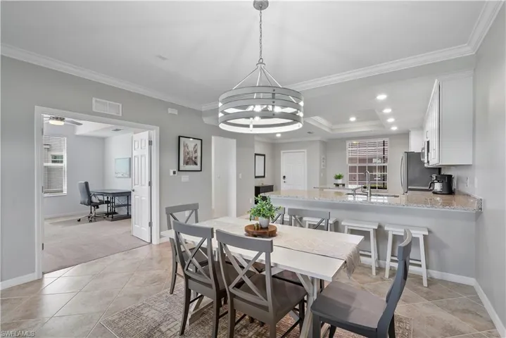 Dining room with a raised ceiling, ornamental molding, recessed lighting, an office area, and light tile patterned floors