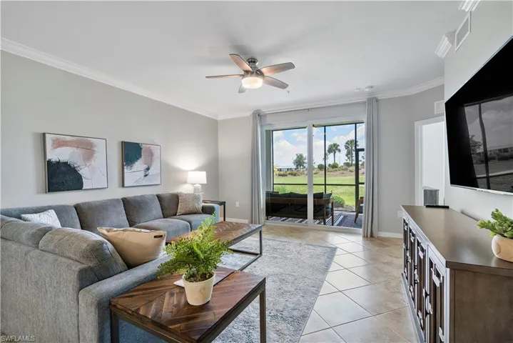 Living area featuring crown molding, light tile patterned flooring, and a ceiling fan