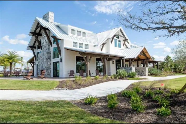 Modern farmhouse style home with a front yard, a metal roof, a chimney, and stone siding