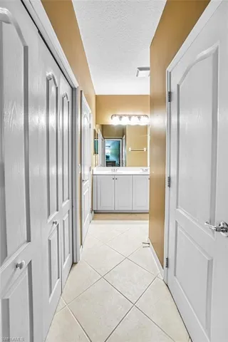 Corridor featuring a textured ceiling and light tile patterned flooring