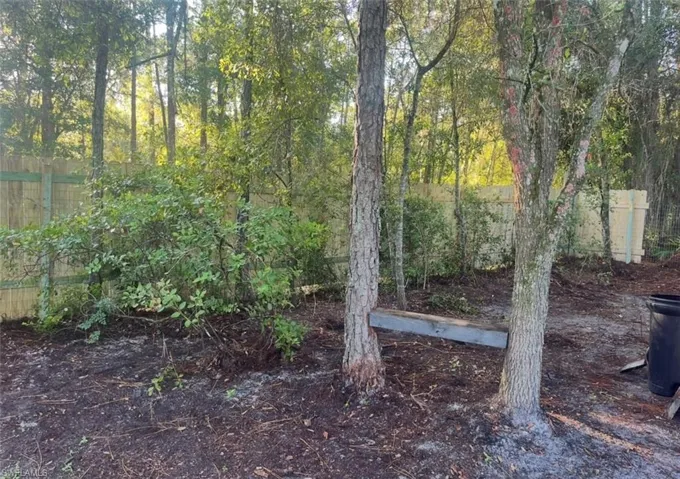 Wood privacy fence enclosing a wooded area with mature trees and ground cover
