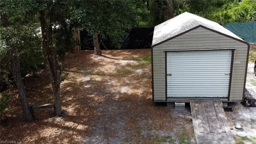 Detached utility shed with a roll-up garage door and an integrated wooden ramp