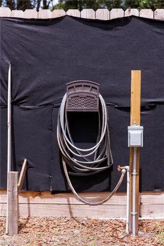 Utility area featuring an exterior water spigot, electrical outlet, and hose reel