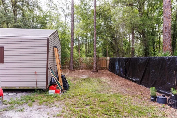 Detached storage shed with horizontal siding and a brown trim roof