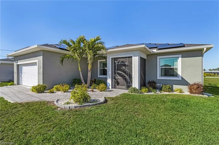 Ranch-style house with a garage, a front lawn, and solar panels