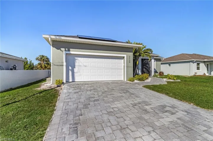 View of front facade with a garage, a front yard, and solar panels