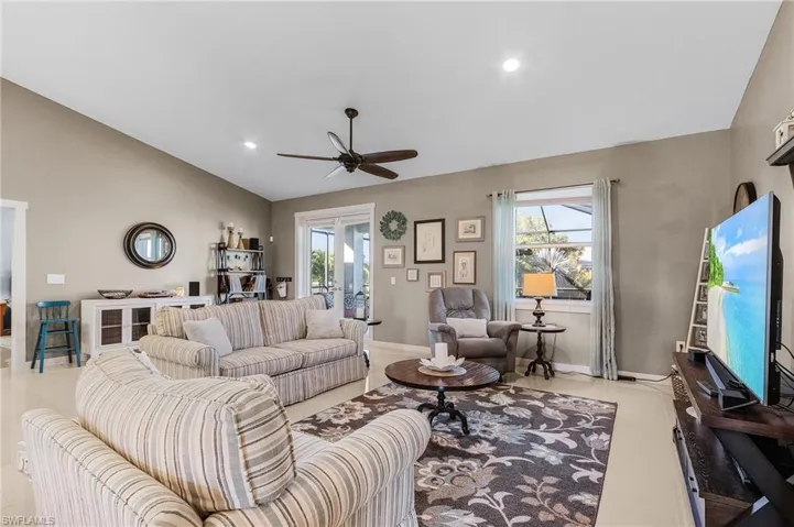 Living room with ceiling fan, plenty of natural light, and vaulted ceiling