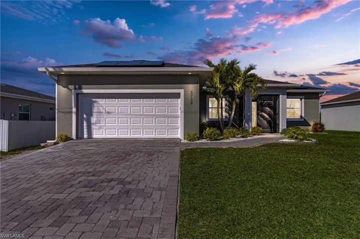Single story home featuring a garage, a yard, and solar panels