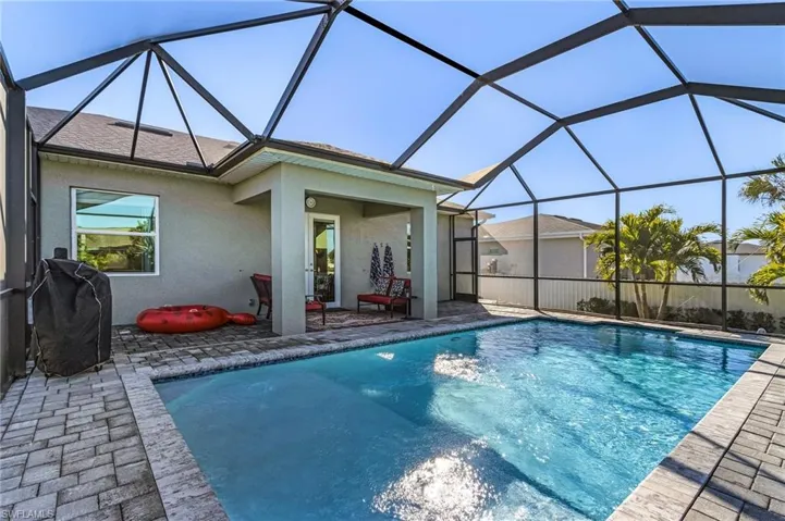 View of pool featuring area for grilling, a patio, and glass enclosure
