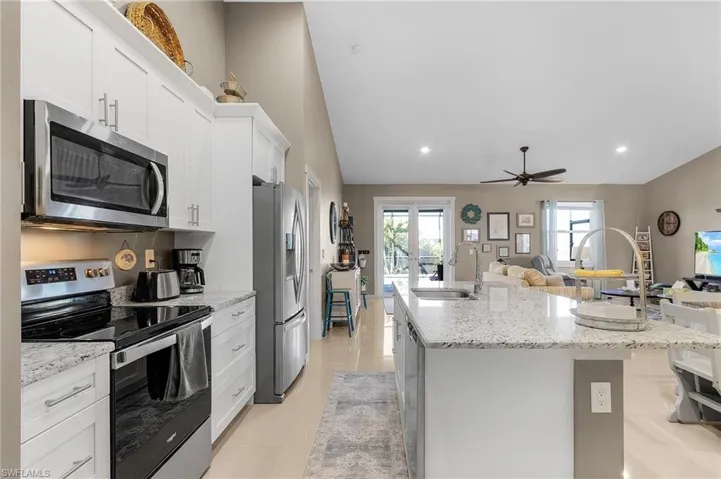 Kitchen featuring white cabinetry, appliances with stainless steel finishes, sink, and a center island with sink