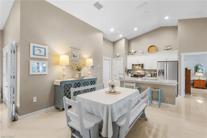 Tiled dining area featuring high vaulted ceiling