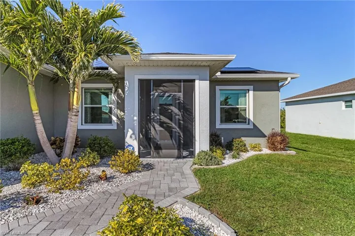 Property entrance with a yard and solar panels