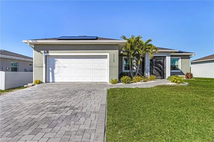 Single story home with a garage, a front yard, and solar panels