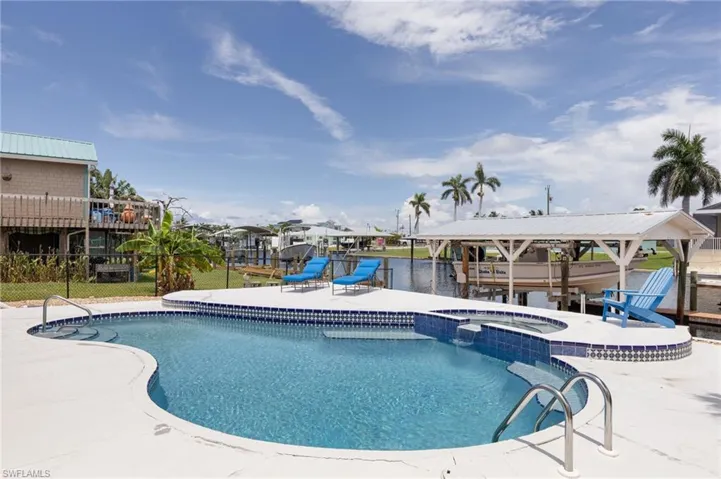 Curved swimming pool with integrated spa and blue mosaic tile surround