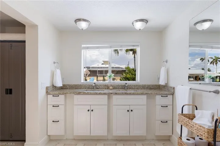 Dual vanity with speckled countertop and white shaker-style cabinetry, featuring brushed nickel hardware, and individual under-mount sinks